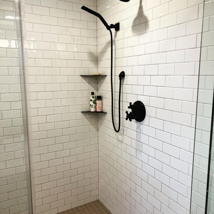 White tiles and black faucet in shower remodel by Reese Builders.